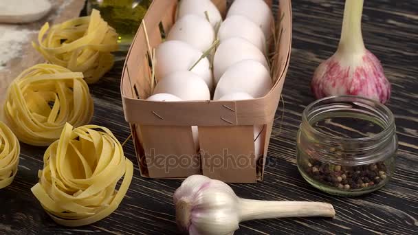Pasta, huevos, ajo, aceite y harina sobre fondo de madera — Vídeos de Stock