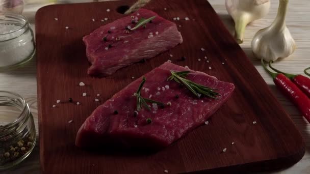 Beef fillet on a desk with pepper, rosemary and garlic. — Stock Video