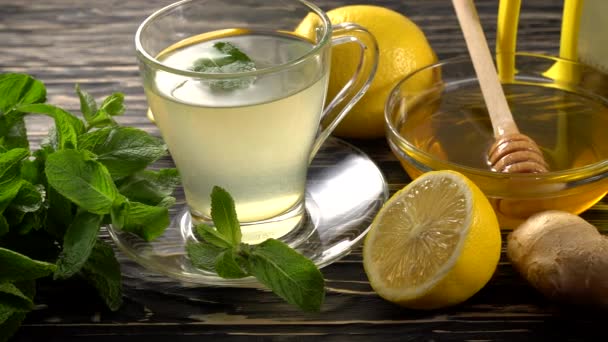 Ginger čaj s citronem, mátou a medem na dřevěné pozadí. — Stock video