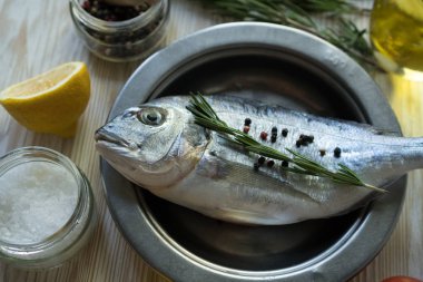 Çiğ balık pişirme ve malzemeler. Dorado, limon, otlar ve baharatlar.