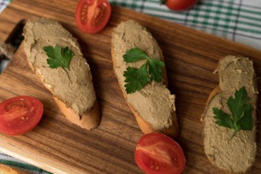Ekmek arası ahşap tepsi üzerinde karaciğer pate.
