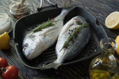 Çiğ balık pişirme ve malzemeler. Dorado, limon, otlar ve baharatlar.