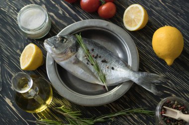 Çiğ balık pişirme ve malzemeler. Dorado, limon, otlar ve baharatlar.