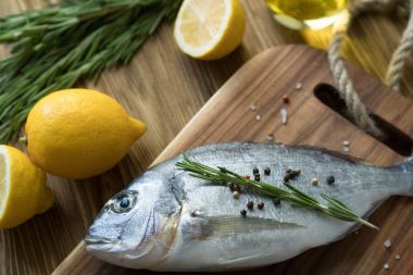 Çiğ balık pişirme ve malzemeler. Dorado, limon, otlar ve baharatlar.