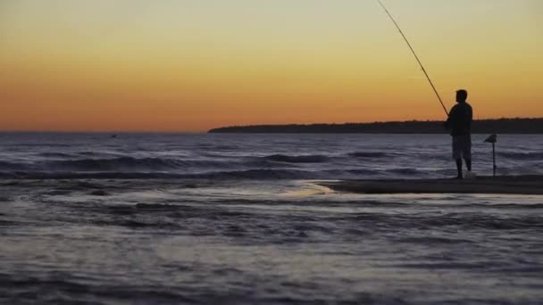 Fisherman with spinning silhouette at sea sunset — Stock Video