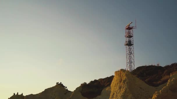Прибрежная радиолокационная антенна, вращающаяся на вершине башни против неба — стоковое видео