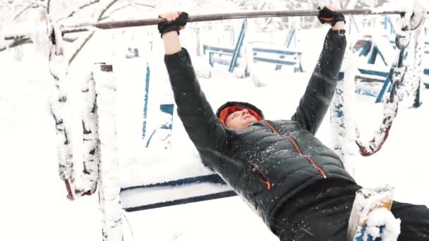 Молодой мускулистый человек тренируется и делает упражнения на открытом воздухе в зимнее время . — стоковое видео