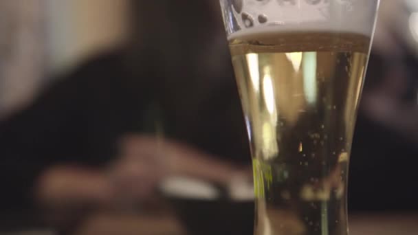 Μετακίνηση φυσαλίδες μέσα σε ένα ποτήρι μπύρα με σταγόνες και αφρός ως φόντο. — Αρχείο Βίντεο
