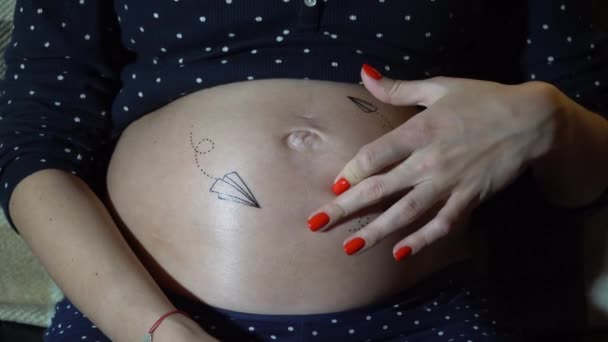 Glückliche schwangere Frau, die auf einem Sofa ruht und ihren Bauch streichelt. — Stockvideo