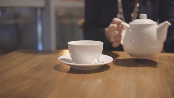 Tetera blanca y taza en una mesa en la cafetería de la ciudad . — Vídeos de Stock