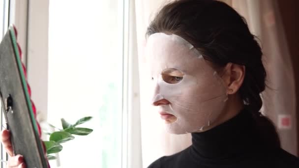 Mujer joven haciendo mascarilla facial con mascarilla purificadora en su cara . — Vídeo de stock