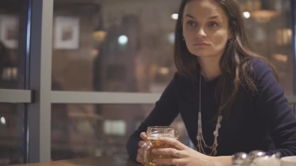 Mujer joven bebiendo cerveza en la cafetería — Vídeos de Stock