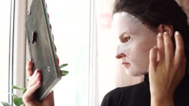 Genç kadının yapması ile yüzünde maske arındırıcı yüz maskesi sayfası.