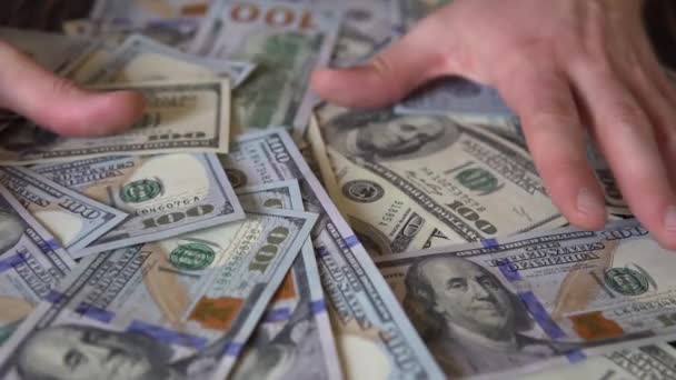 Рука грабит долларовые купюры на деревянном столе, на фоне банкнот — стоковое видео