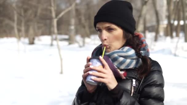 Замороженная девушка пьет кофе зимой на улице — стоковое видео
