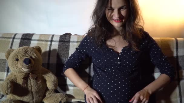 Heureuse femme enceinte reposant sur un canapé et caressant son ventre . — Video