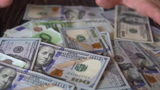 Рука грабит долларовые купюры на деревянном столе, на фоне банкнот — стоковое видео