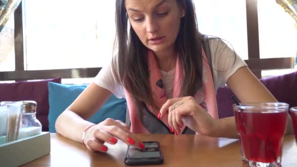 Hermosa mujer se sienta en el café utiliza Smartphone . — Vídeos de Stock