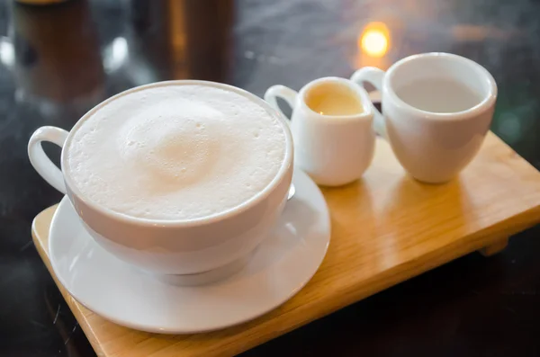 Taza de leche en plato de madera en mesa de vidrio — Foto de Stock