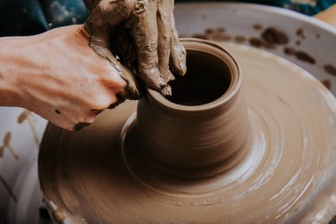 Çömlekçi çarkında çalışan kadınlar. Eller kilden bir kap yontuyor. Çömlekçi çarkında modellik üzerine atölye.