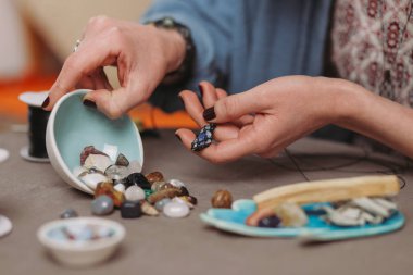 El yapımı mücevher yapan bir kadın, ev yapımı atölye çalışması. Zanaatkar kadın mücevher üretir. Sanat, hobi, el işi konsepti