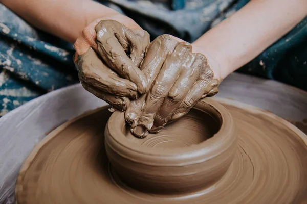 Women working on the potter\'s wheel. Hands sculpts a cup from clay pot. Workshop on modeling on the potter\'s wheel.