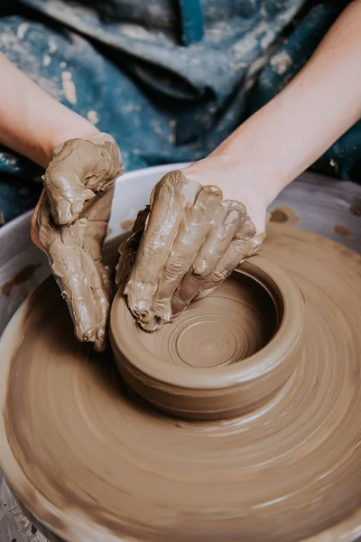 Women working on the potter\'s wheel. Hands sculpts a cup from clay pot. Workshop on modeling on the potter\'s wheel.