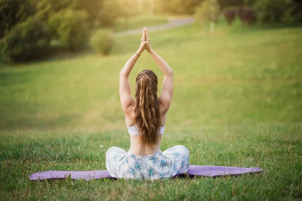 Dışarıda yoga yapan genç bir kadın. Yeşil bulanık arkaplan