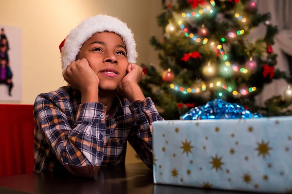 Dziecko siedzi obok świąteczny prezent. — Zdjęcie stockowe