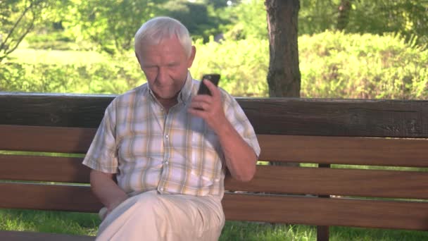 Oudere man met telefoon smiling. — Stockvideo