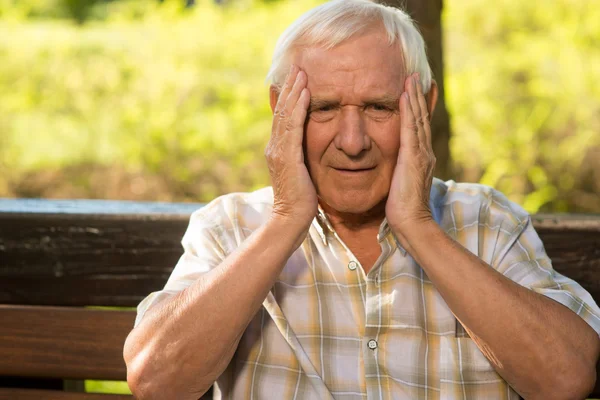 Elderly man holds his head. — Stock Photo, Image