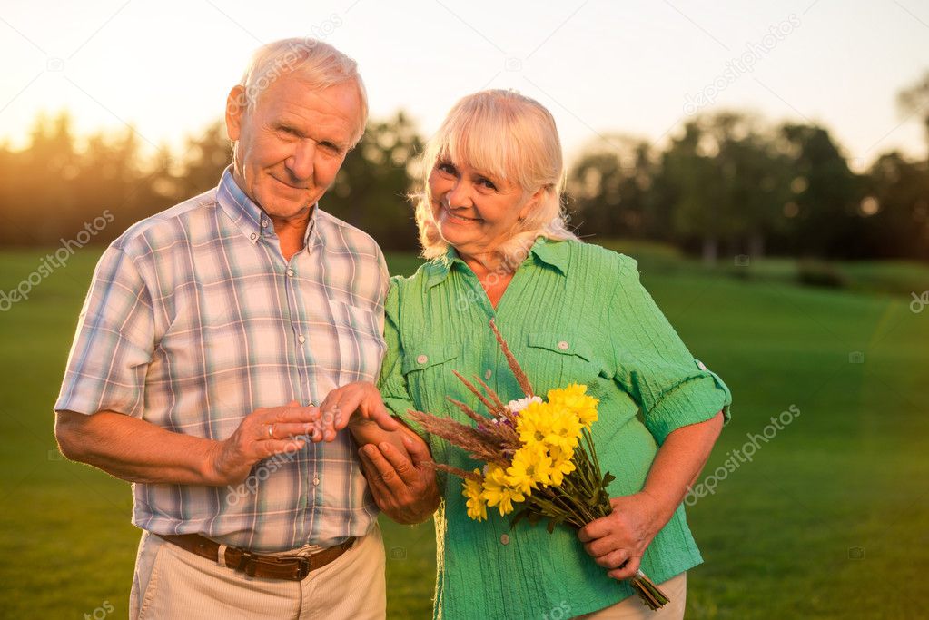 Senior couple with bouquet smiling.