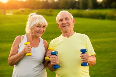 Çift dambıl ile gülümsüyor.