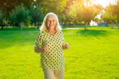 Yaşlı kadın ayakta ve gülümsüyor..