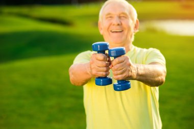 Yaşlı adam dumbbells tutuyor.
