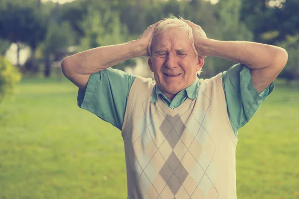 Elderly man holding his head. — Stock Photo, Image
