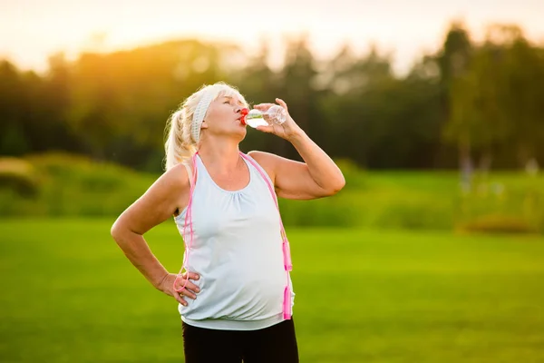 Old woman with sports bottle. — Stock Photo, Image