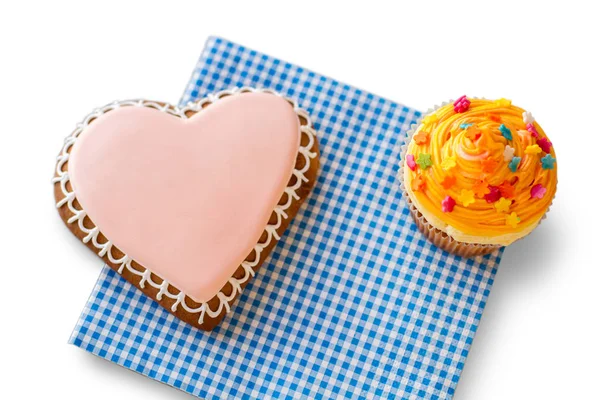 Heart biscuit and orange cupcake. — Stock Photo, Image