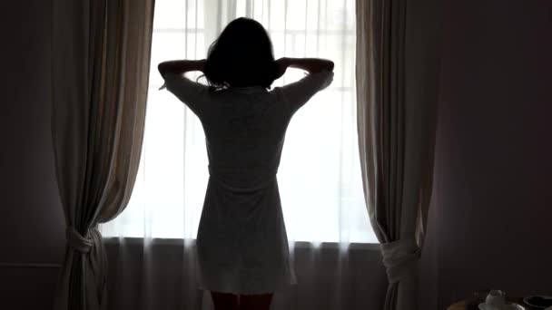 Kobieta stoi obok okna. — Wideo stockowe