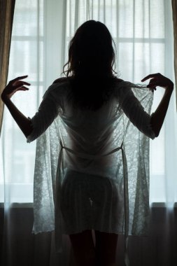 Pencere yakınındaki kadın ayakta.
