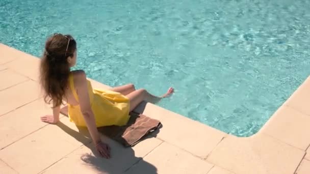Woman sitting near swimming pool. — Stock Video