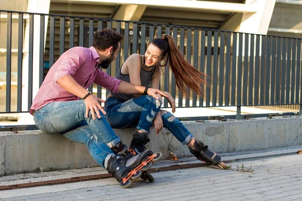 Couple on rollerblades is sitting. — Stock Photo, Image