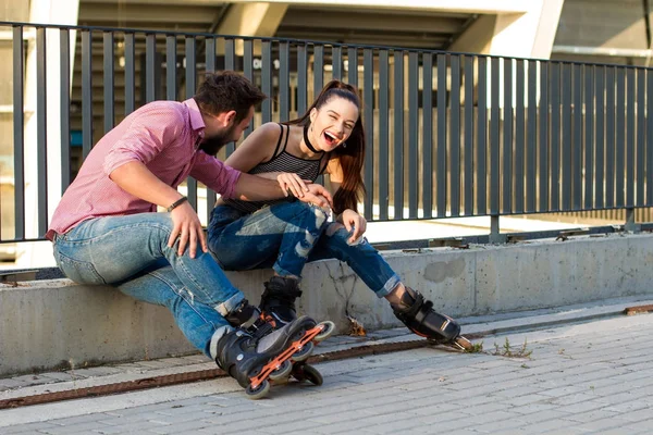 Two people on rollerblades sitting. — Stock Photo, Image