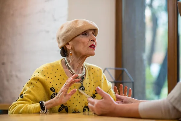 Elderly woman talking at table. — Stock Photo, Image