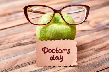 Gözlük, tebrik kartı ve elma.