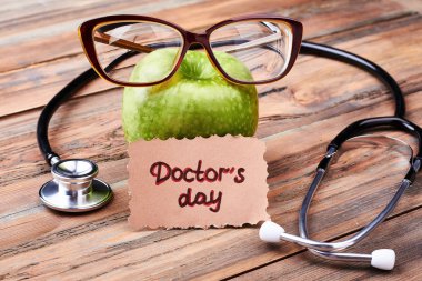 Stetoskop, gözlük, elma ve kart.