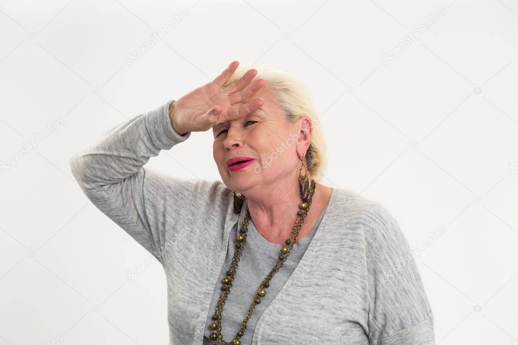 Senior woman touching her forehead.