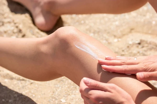 Леди наносит солнцезащитный крем на ногу . — стоковое фото