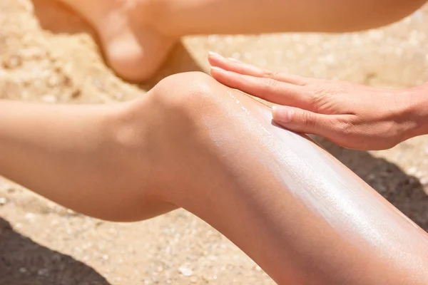 Девушка наносит солнцезащитный крем на ногу . — стоковое фото