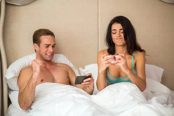 Menschen im Bett mit Telefonen. — Stockfoto